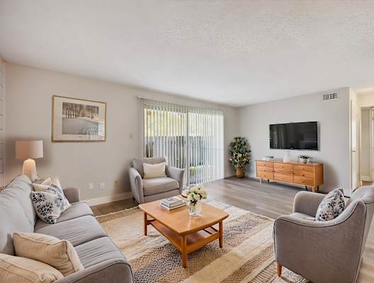 A living room with a grey couch, a wooden coffee table, and a flat screen TV.