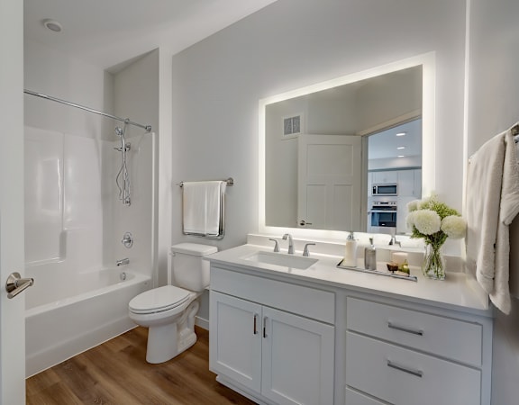 a white bathroom with a large mirror and a white toilet and sink