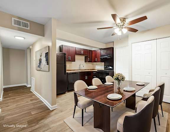 A dining room with a table set for two and a kitchen in the background.
