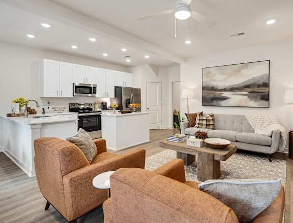 A modern living room with a kitchen in the background.