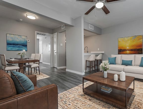 A living room with a brown leather couch and a painting of a sunset on the wall.