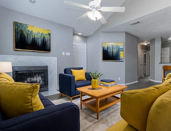 A living room with a fireplace, two couches, a coffee table, and two paintings on the wall.