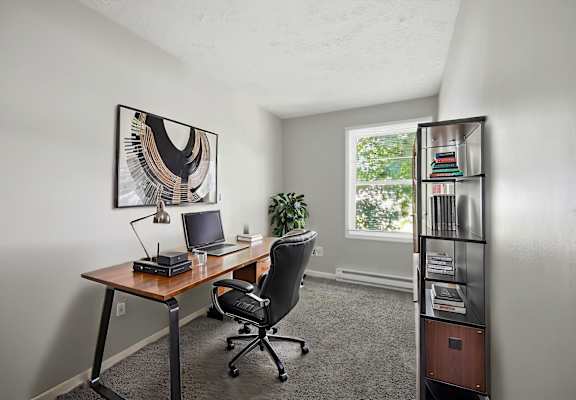 A room with a desk, chair, and bookshelf.
