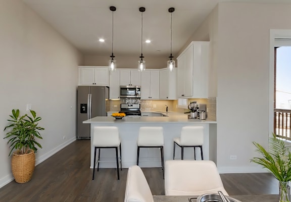 an open kitchen and dining room with white cabinets and a large island with white chairs