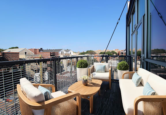 Private balcony in 3 bedroom apartment at Highpoint Lincoln Park on Fullerton with white chairs and wooden table