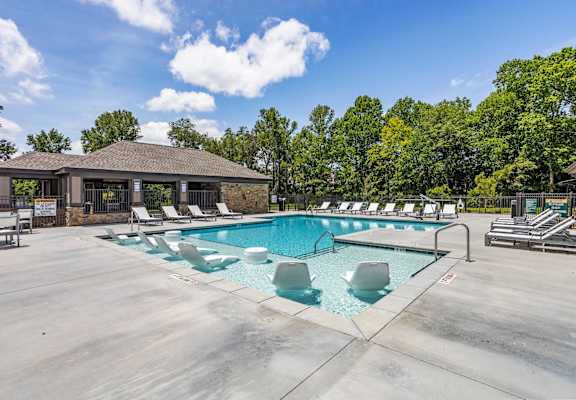 the resort style pool with lounge chairs and a building in the background