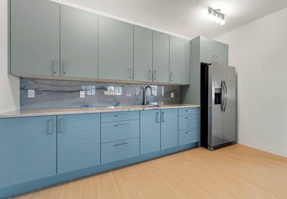 A kitchen with blue cabinets and a black refrigerator.at The Teale New Haven Apartments, Melbourne, FL, 32904