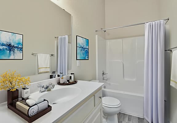 A bathroom with a white tub, sink, and toilet.