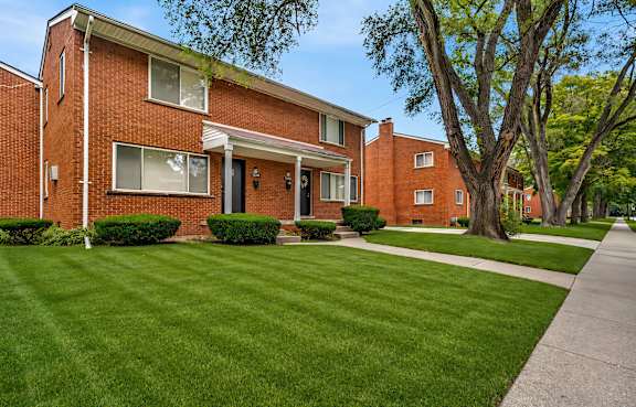 A red brick house with a green lawn in front. at Oak Park Gardens, Oak Park, MI 48237