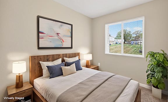 A bedroom with a large bed, a lamp, a painting, and a potted plant.