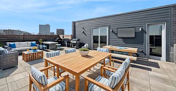 A wooden table is surrounded by chairs on a patio.