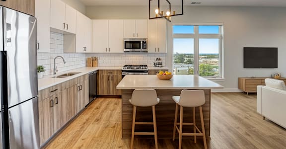 a kitchen with white cabinets and a white island with three chairs