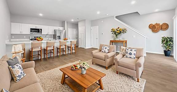A living room with a brown couch, two chairs, and a coffee table.