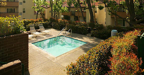 a swimming pool with two lounge chairs in front of an apartment building