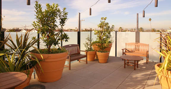 a roof terrace with tables and benches and potted plants