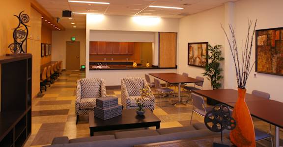 a large living room with tables and chairs and a kitchen