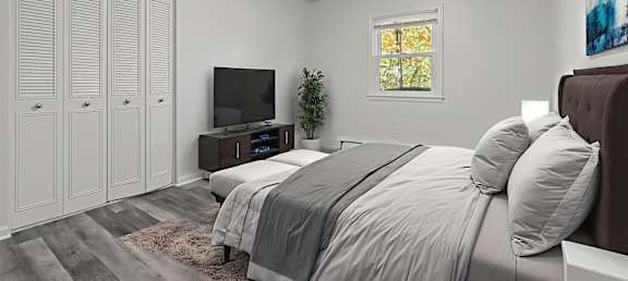 A bedroom with a bed, a television, and a window.