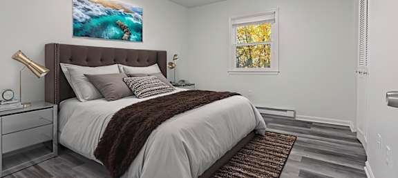 A bedroom with a large bed and a painting of a beach scene on the wall.