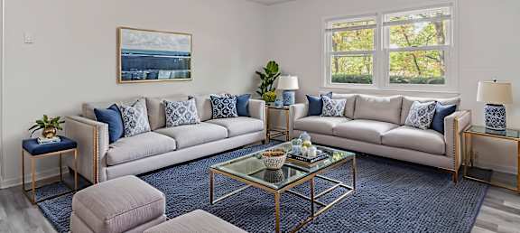 A living room with a large couch, a coffee table, and a painting on the wall.