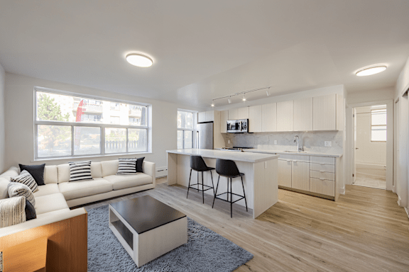 A modern living room with a white sofa and a kitchen area in the background.at 111 Cosburn, Ontario