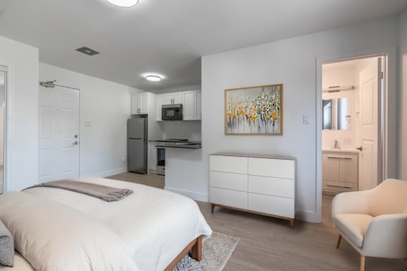 A bedroom with a bed, a chair, and a painting on the wall. at 608 Church Apartments, Toronto, ON, M4Y 2E7