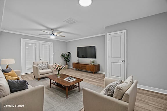 A living room with a ceiling fan, a couch, a chair, a coffee table, and a television.