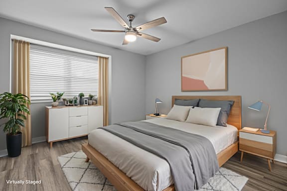 A bedroom with a bed, nightstands, and a ceiling fan.