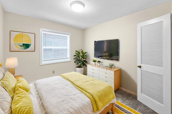 A bedroom with a bed, nightstand, and a window.