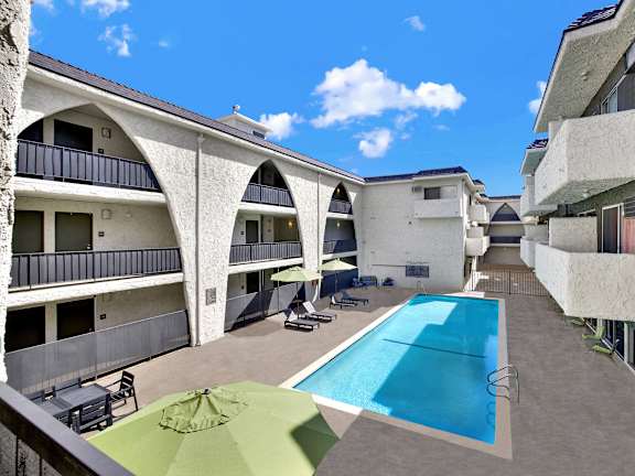 A swimming pool is surrounded by a concrete floor and a green umbrella. at Bonnie Brae Apartments, California