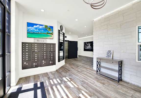 A modern interior with a wooden floor and a large painting of a beach scene on the wall.