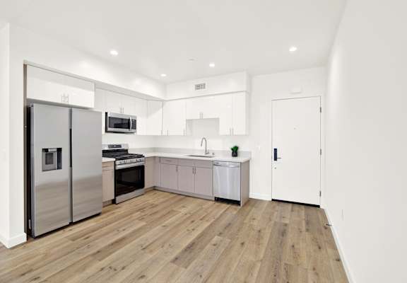A modern kitchen with wooden floors and white walls.