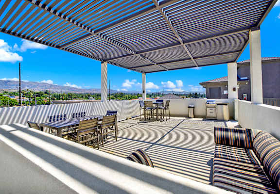 A patio with a striped couch and a striped umbrella.