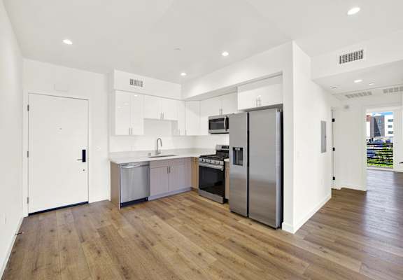 A modern kitchen with wooden floors and stainless steel appliances.