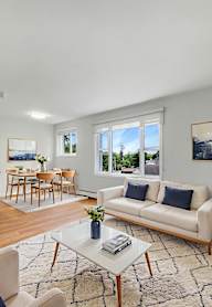 A living room with a white couch, a coffee table, and a dining table with chairs.