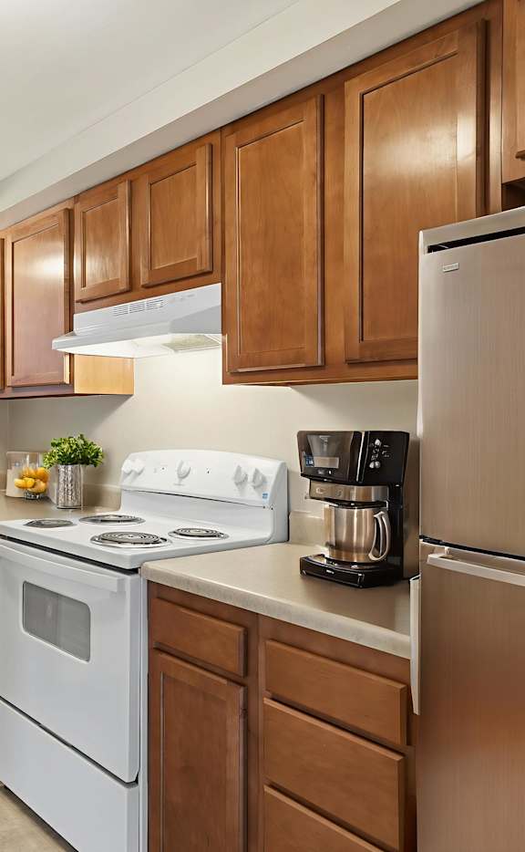 A kitchen with white appliances and wooden cabinets.