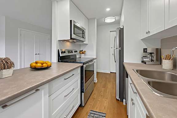 A kitchen with white cabinets and a black refrigerator.