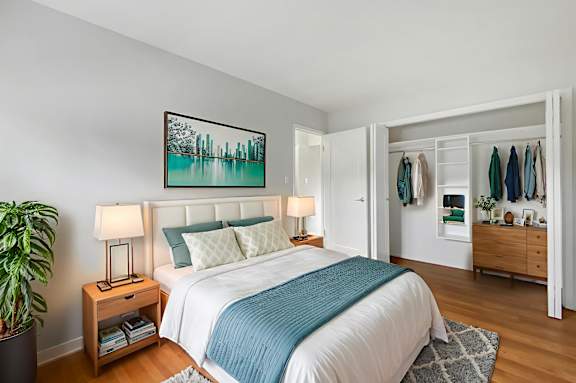 A bedroom with a bed, nightstand, and a painting on the wall.
