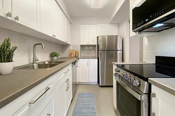 A modern kitchen with white cabinets and stainless steel appliances.