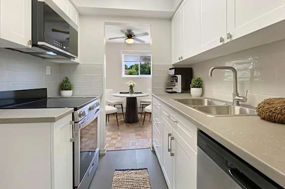 A modern kitchen with white cabinets and a black stove top oven.