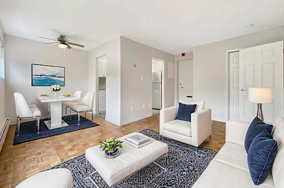 A living room with a white couch, a white dining table, and a ceiling fan.