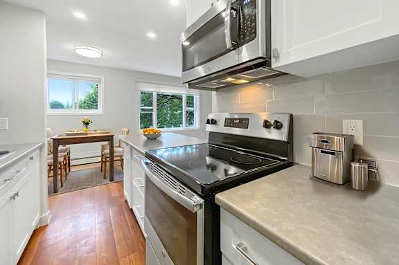 A modern kitchen with a black stove top oven and white cabinets.