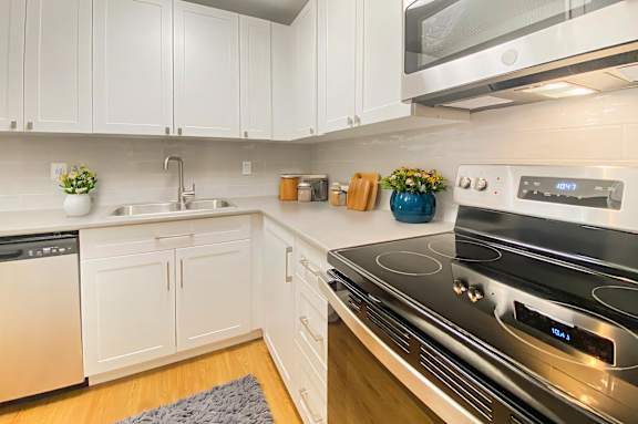 A modern kitchen with white cabinets and a stainless steel stove.