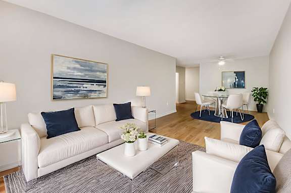 A living room with a white couch and a painting on the wall.