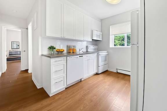 A kitchen with white cabinets and appliances.
