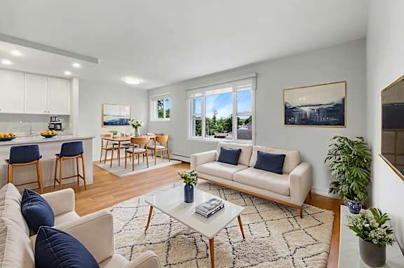 A living room with a white couch, a coffee table, and a dining table with chairs.