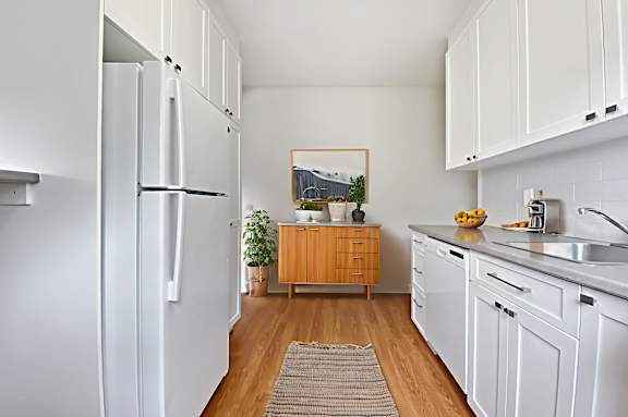 A kitchen with white cabinets and a white refrigerator.