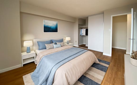 A bedroom with a bed, nightstands, and a painting on the wall.