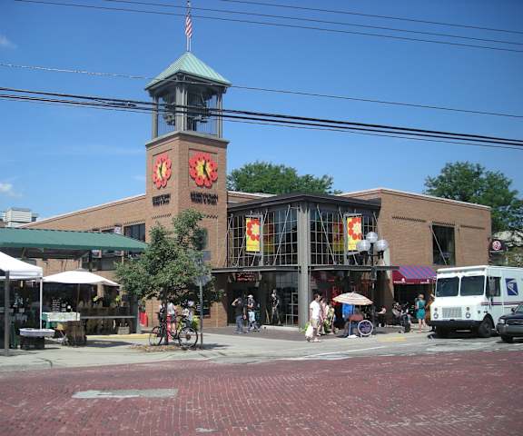 A brick building with a clock tower in the middle of a street.