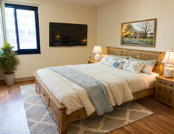 A bedroom with a bed, nightstands, and a painting on the wall.
