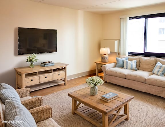 A living room with a couch, a coffee table, and a television mounted on the wall.
